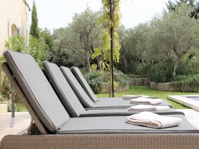a row of lounge chairs sitting on a patio at Mas in Eygalières with Heated Pool in Eygalières