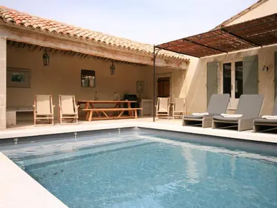 a swimming pool with chairs and a table at Mas in Eygalières with Heated Pool in Eygalières