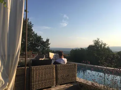 a man sitting on a balcony looking at the view at Une Sieste en Luberon in Bonnieux