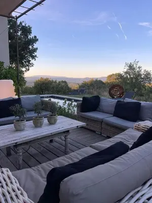 a patio with couches and a table on a deck at Une Sieste en Luberon in Bonnieux