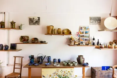 a room with a wooden table with ceramics on the wall at Poterie de Pierroux in Roussillon