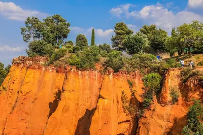 a cliff with trees on top of it at Poterie de Pierroux in Roussillon
