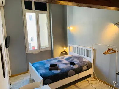 a small bedroom with a bed with a blue blanket at Mirabeau Studio in Aix-en-Provence