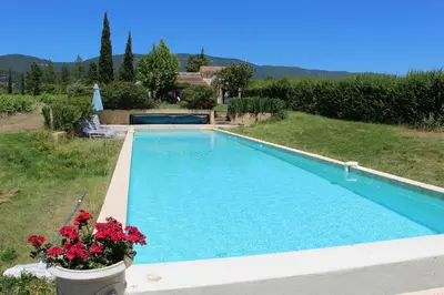 a swimming pool in a yard with flowers at La Bastide des Vasses l'Atelier in Cucuron