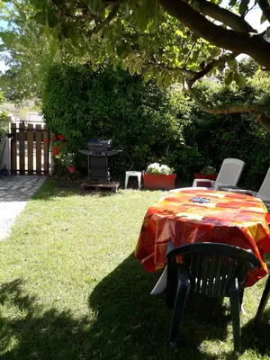 a table and chairs in a yard with a grill at Brig'Gîte in LʼIsle-sur-la-Sorgue
