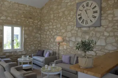 a living room with a large clock on a stone wall at Les Gîtes Du Clos D'Olea in Oppède