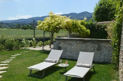 two white chairs and a table in the grass at Les Gîtes Du Clos D'Olea in Oppède
