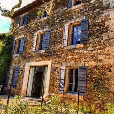 an old stone building with blue shutters on it at Les Gîtes Du Clos D'Olea in Oppède