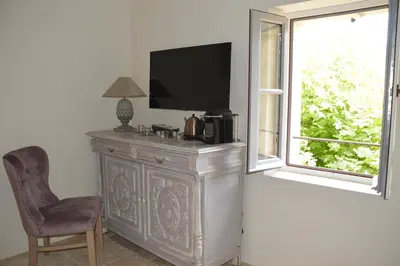 a tv sitting on top of a dresser next to a window at Le Clos D'Olea in Oppède