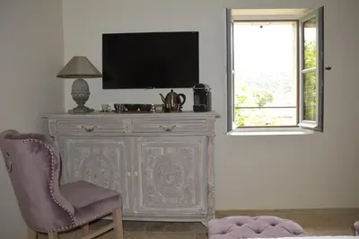 a television on top of a dresser with a chair at Le Clos D'Olea in Oppède