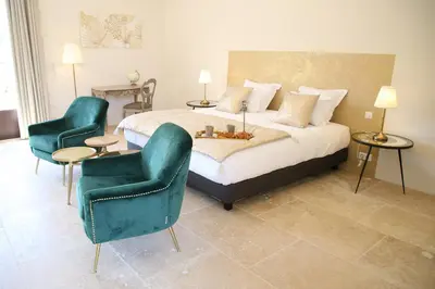 a bedroom with a bed and two chairs at Le Clos D'Olea in Oppède