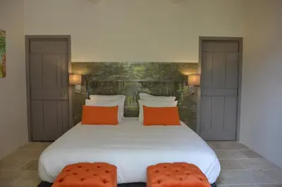 a bedroom with a large white bed with orange pillows at Le Clos D'Olea in Oppède