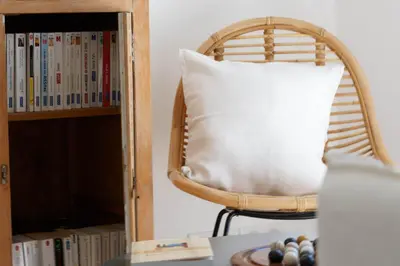 a pillow on a chair next to a book shelf at Le Mas de Garrigon - Boutique Hôtel & Spa in Roussillon