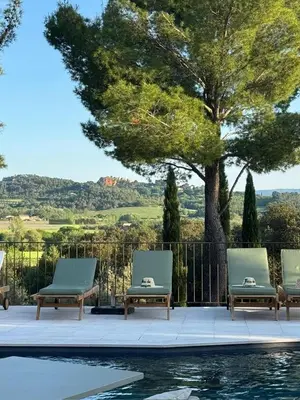 a pool with three lounge chairs next to a tree at Le Mas de Garrigon - Boutique Hôtel & Spa in Roussillon