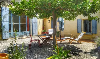 a table and chairs under a tree in front of a house at La Bastide des Vasses 