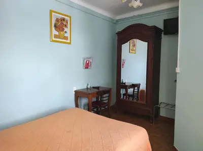 a bedroom with a bed and a mirror and a table at Hotel Régina in Salon-de-Provence