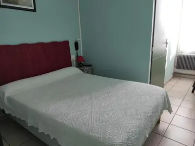 a bedroom with a bed with a white comforter at Hotel Régina in Salon-de-Provence
