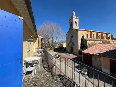 a balcony with a table and chairs and a church at La Sarrasine in Villes-sur-Auzon
