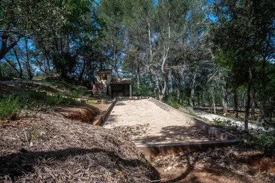 a concrete path in the middle of a forest at Stunning panoramic views and heated pool in Roussillon in Roussillon