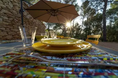 a table with two yellow plates and an umbrella at Stunning panoramic views and heated pool in Roussillon in Roussillon
