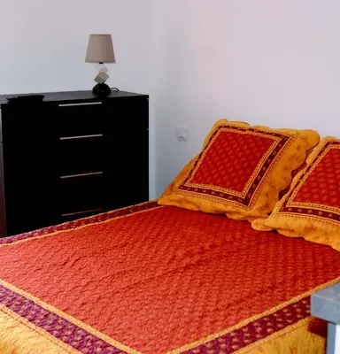 a bedroom with a bed with orange and red pillows at La goutte d'or in Roussillon