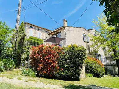 a house with an umbrella in front of a bush at Gîte La Bastide de La Loge au pied du Mont Ventoux in Sault-de-Vaucluse