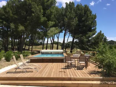 a deck with a table and chairs next to a pool at typical provencal farm in an exceptional natural site, the alpilles park - 8 people. in Maussane-les-Alpilles