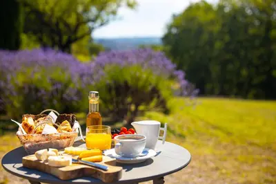 a table with food and drinks and a basket of bread at Le Mas Sérénité in Ansouis