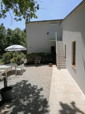 a white building with a table and an umbrella at Le Clos Zinou in Lambesc