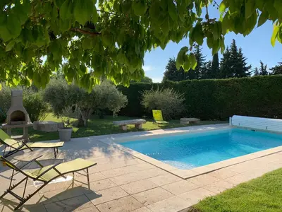 a swimming pool in a yard with two chairs and a table at Le Mazet Des Joncs en Provence in Saint-Pierre-de-Vassols