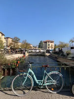 a bike parked next to a river with a bridge at Le 40 in LʼIsle-sur-la-Sorgue