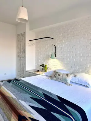 a bedroom with a large bed with a white brick wall at Le 40 in LʼIsle-sur-la-Sorgue