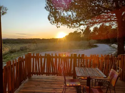 a table and chairs on a wooden deck with the sunset at Domaine de Villemus in Jouques