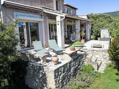 a house with two chairs and a stone wall at Villa La Chênaie by Interhome in Saumane-de-Vaucluse