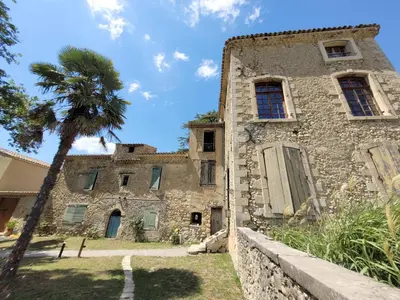 an old stone building with a palm tree in front of it at la bastide de l'adrech in Manosque
