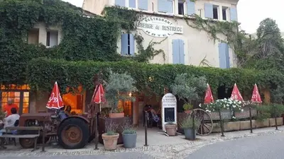 a building with red umbrellas in front of it at Auberge de Rustréou in Rustrel