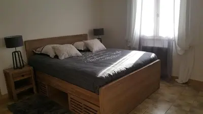 a bedroom with a bed with a wooden frame and a window at Les Prairies de l'Encrême in Céreste