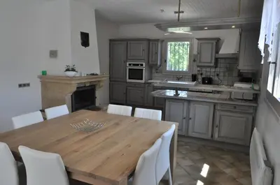 a kitchen with a wooden table and white chairs at Les Prairies de l'Encrême in Céreste