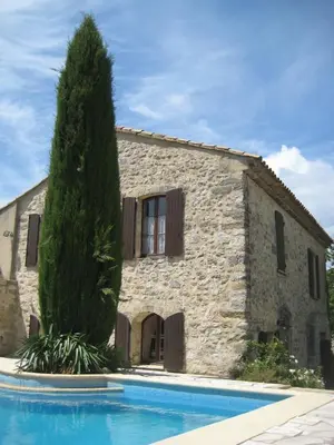 a stone house with a swimming pool in front of it at La Fenice - Beautifully restored property with heated pool in small village in Montjustin