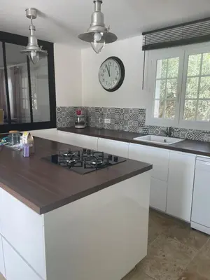 a kitchen with white cabinets and a clock on the wall at Villa Le Luberon in Mérindol