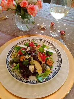 a plate of salad on a table with a glass of wine at Mas de Karlotte in Pernes-les-Fontaines