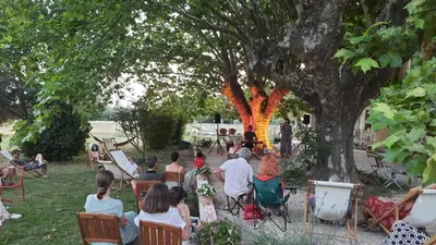 a group of people sitting in chairs under a tree at Mas de Karlotte in Pernes-les-Fontaines