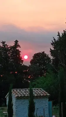 a sunset with the sun in the sky behind trees at Mas de Karlotte in Pernes-les-Fontaines