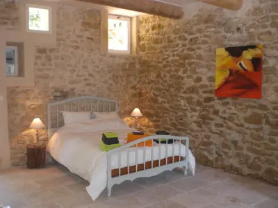 a bedroom with a white bed in a stone wall at Château de Peyrolles in Apt