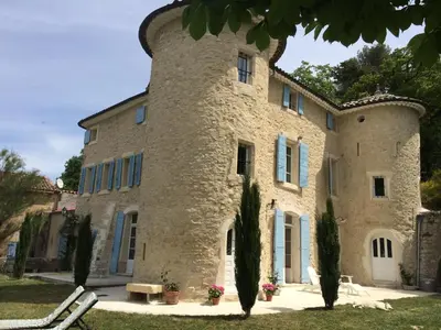 a large stone building with blue shutters at Château de Peyrolles in Apt
