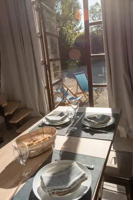 a table with plates and glasses on a table with a window at Le Champ des Oliviers in Oppède
