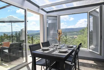 a dining room with a table and glass windows at Domaine du Val de Sault in Sault-de-Vaucluse