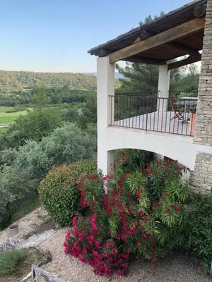 a balcony of a house with pink flowers at Le Logis in Gordes