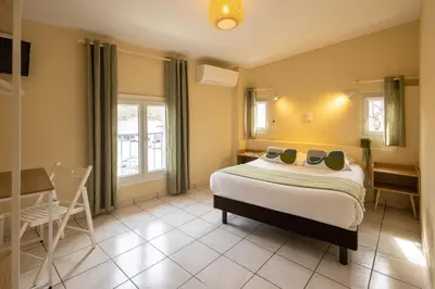 a bedroom with a bed and a table and chairs at L'Aptois Hôtel in Apt