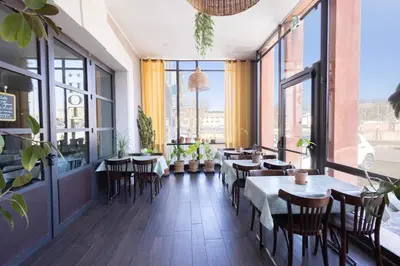 a restaurant with tables and potted plants in a hallway at L'Aptois Hôtel in Apt